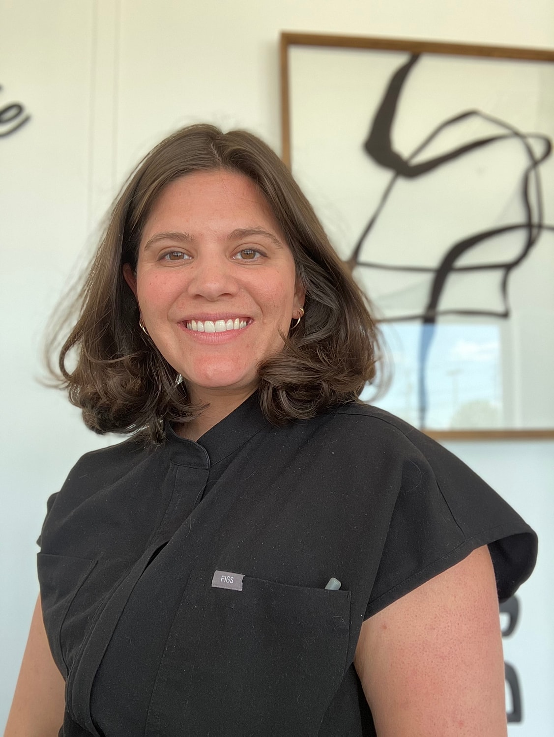 Smiling master esthetician in scrubs.