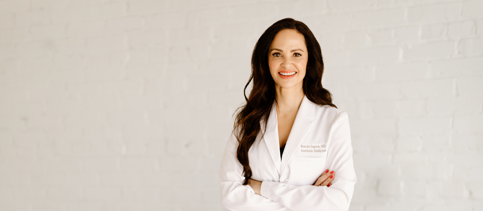 Smiling doctor in a white coat, arms crossed.