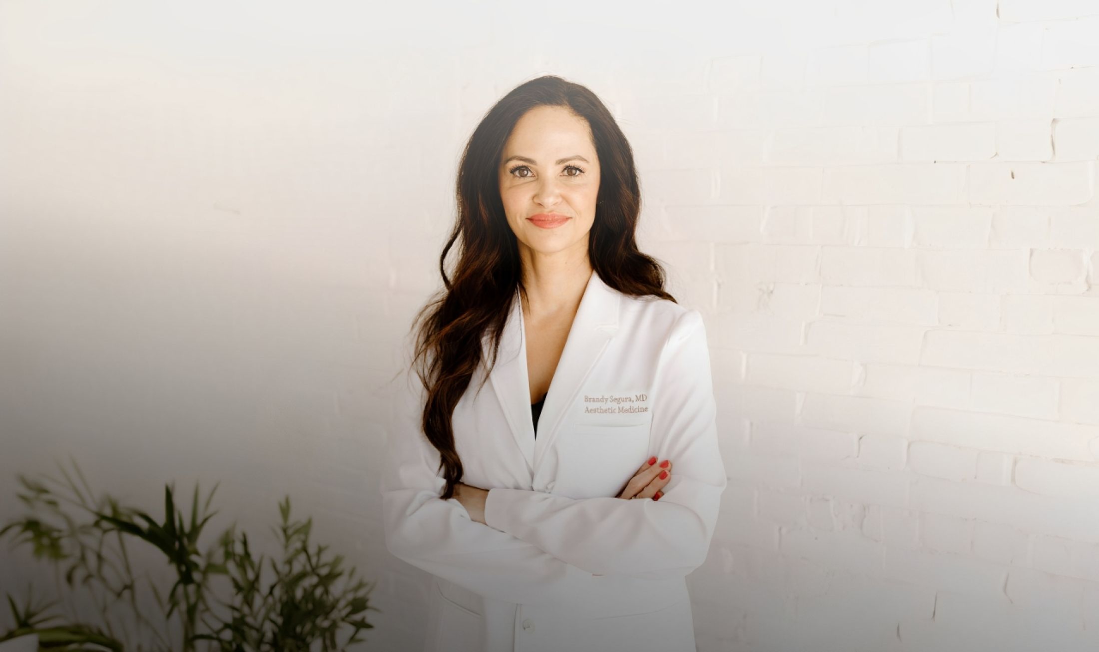 Female doctor in a white coat, smiling confidently.