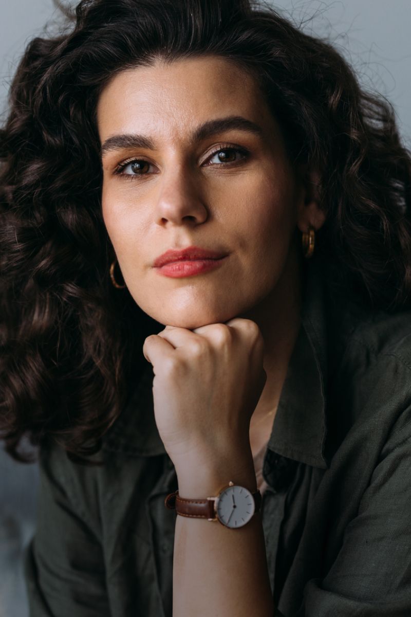 Woman with curly hair resting her chin thoughtfully